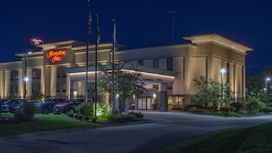A hotel with a prominent neon sign, a parking lot, and a well-lit entrance. - Hampton Inn Medina (Medina)