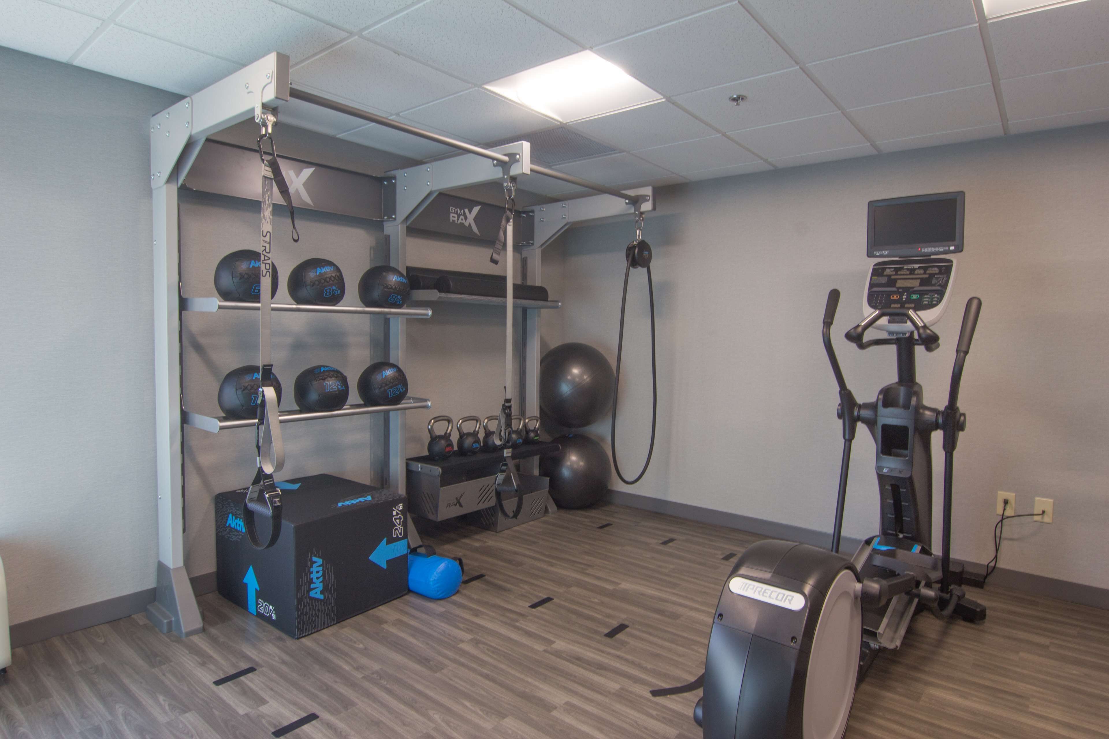 A fitness room with exercise equipment, including a treadmill, stationary bike, and various weights and exercise balls.