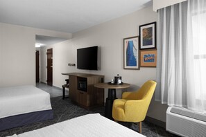 A hotel room with a bed, a desk with a flat-screen TV, a small table, a yellow armchair, and a wall with framed pictures. - Hampton Inn Terre Haute (Terre Haute)