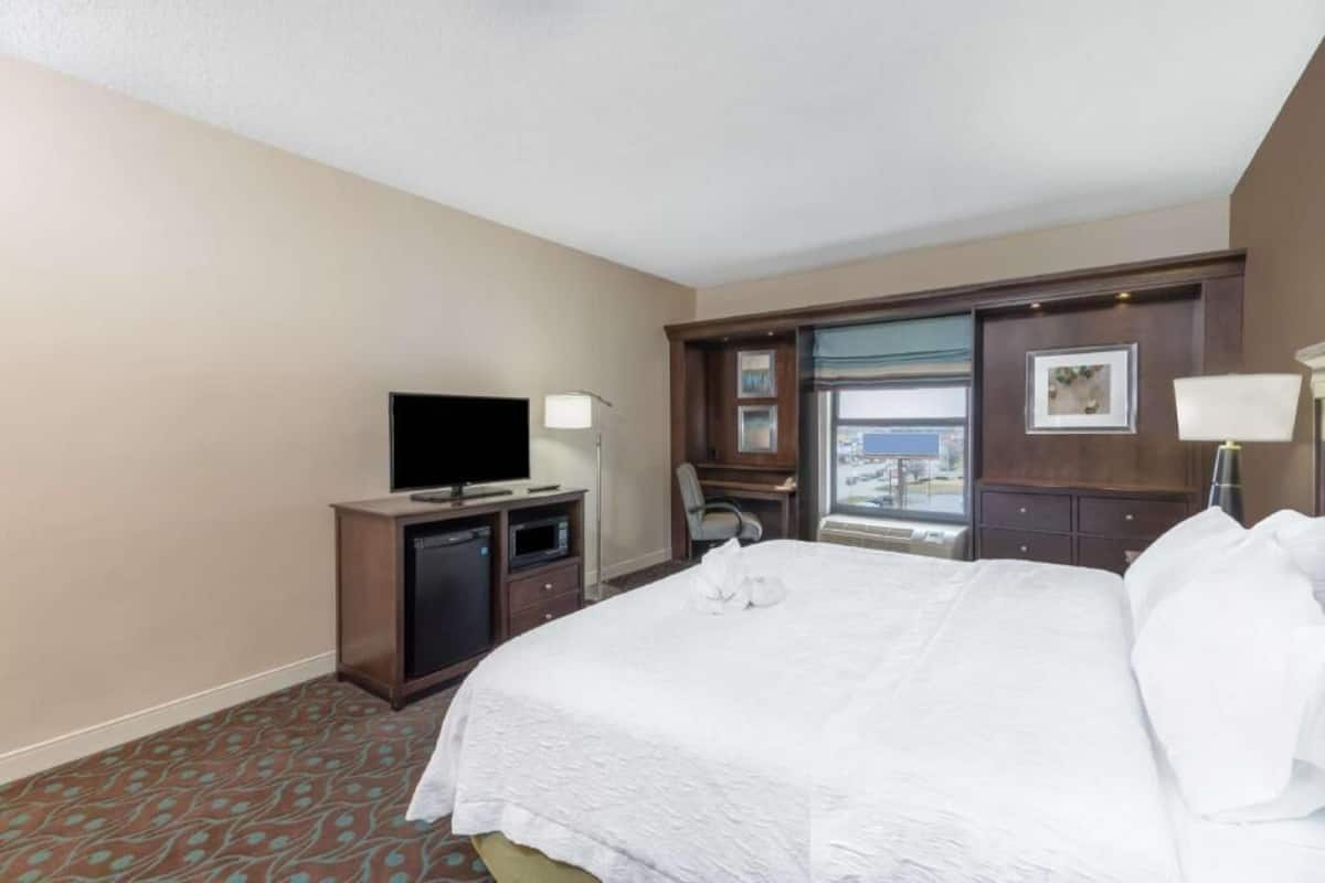 A hotel room with a bed, a television, a desk, and a window with a view.