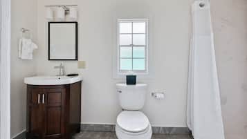 A bathroom with a white toilet, a sink with a mirror above it, and a window above the toilet.
