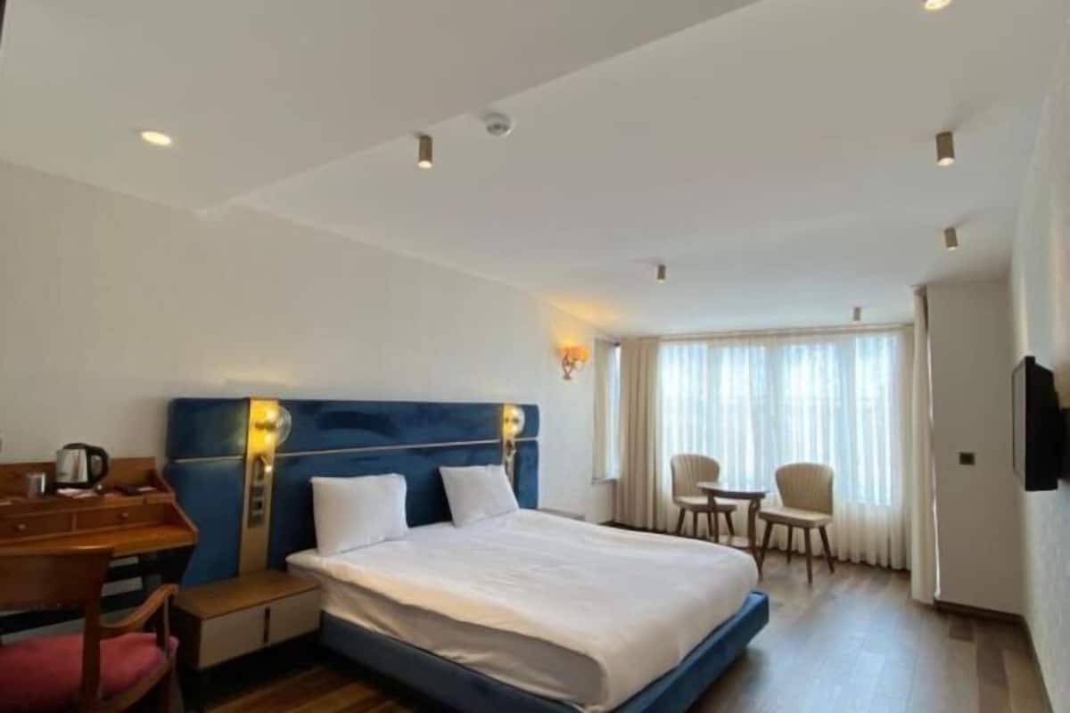Una habitación de hotel con una cama, un escritorio, una silla y un televisor.