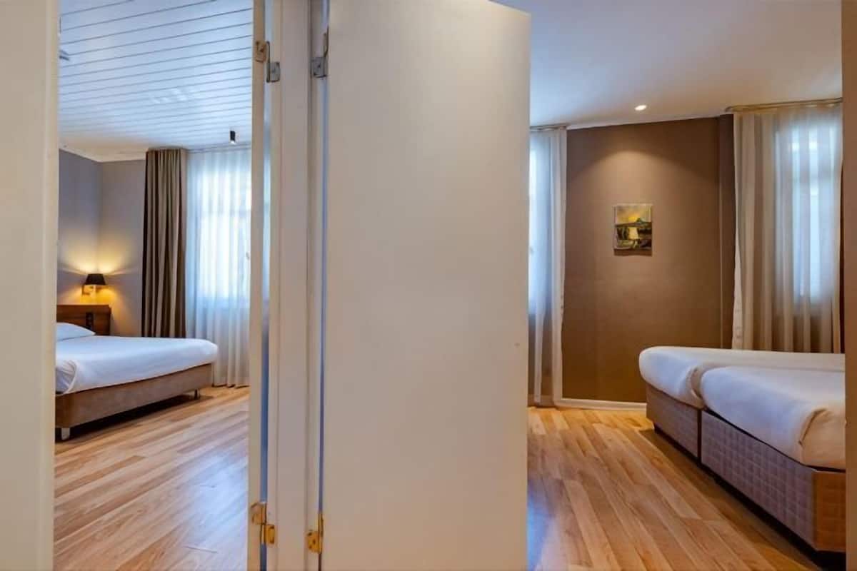 Una habitación de hotel con cama, sofá, mesita de noche y lámpara de pared.