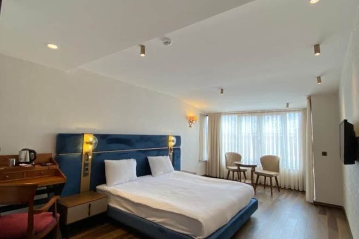 A hotel room with a bed, a desk, a chair, and a TV.