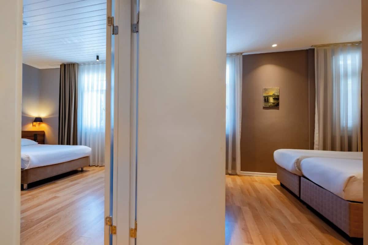 Una habitación de hotel con cama, mesita de noche, lámpara y un cuadro en la pared.