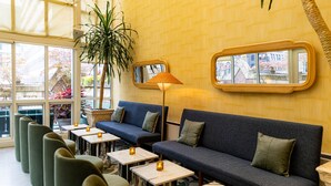 Un espace détente moderne avec des canapés et des tables, un grand miroir et une plante en pot.