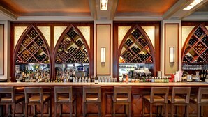 Un espace bar doté d’un présentoir à bouteilles de vin, de tabourets de bar et d’un comptoir bien garni.