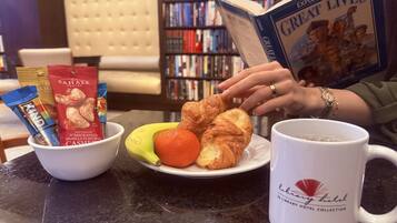 A table with snacks, fruits, and a coffee mug in a library setting.