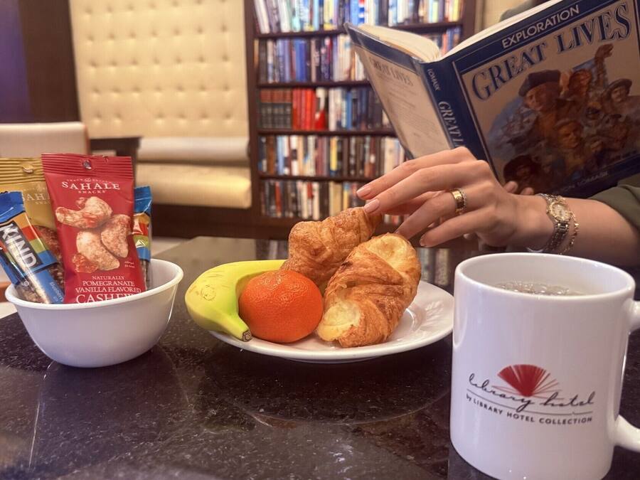A table with snacks, fruits, and a coffee mug in a library setting.