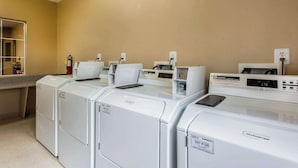 Uma lavanderia com quatro máquinas de lavar de carregamento frontal e um painel de controle digital.