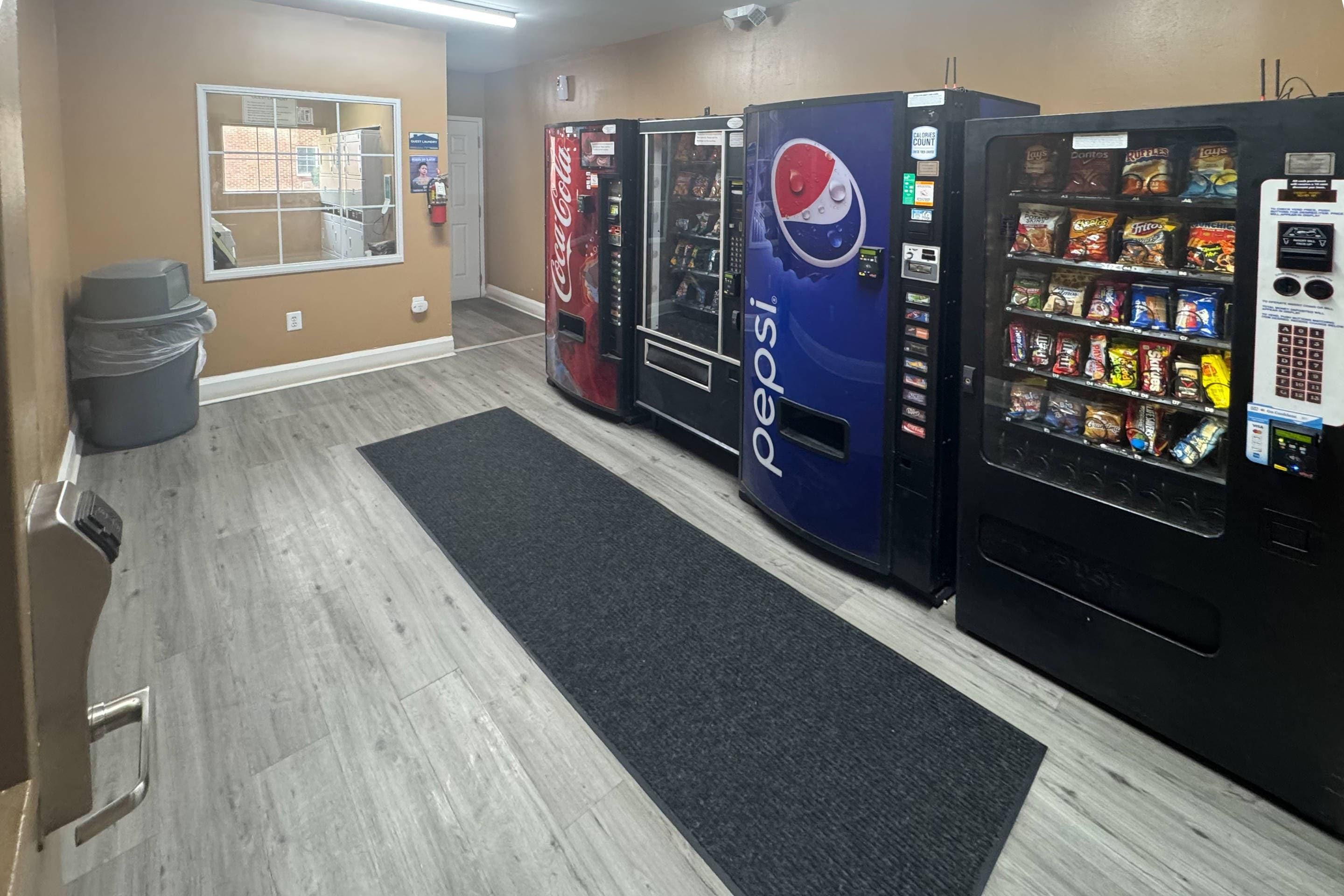 A hotel lobby with vending machines, a trash bin, and a window with a view.