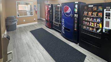 A hotel lobby with vending machines, a trash bin, and a window with a view.