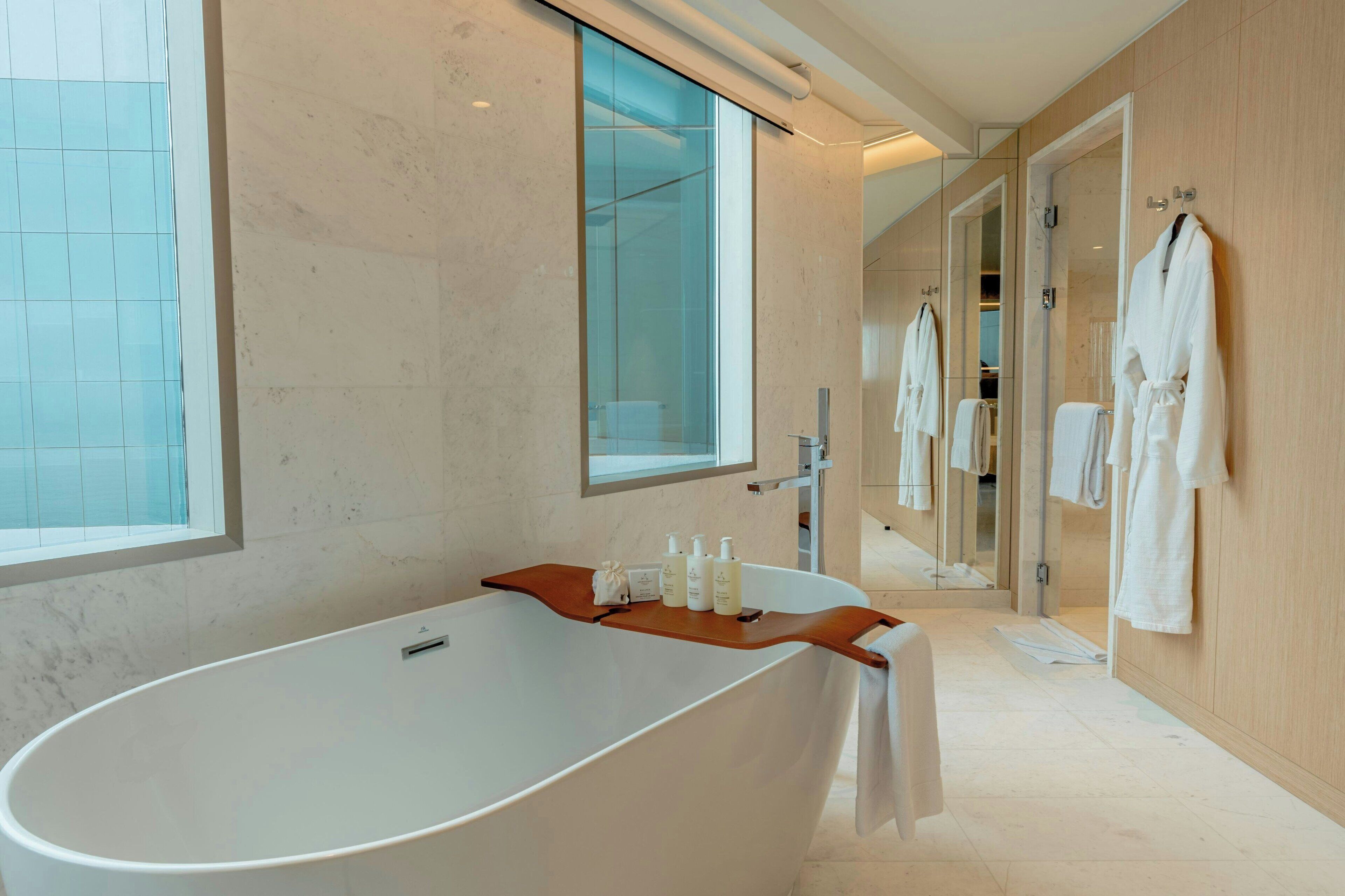 A modern bathroom with a freestanding bathtub, a large mirror, and a wooden vanity.