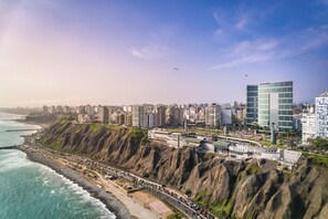 Paisagem costeira com edifícios altos, uma praia e falésias.