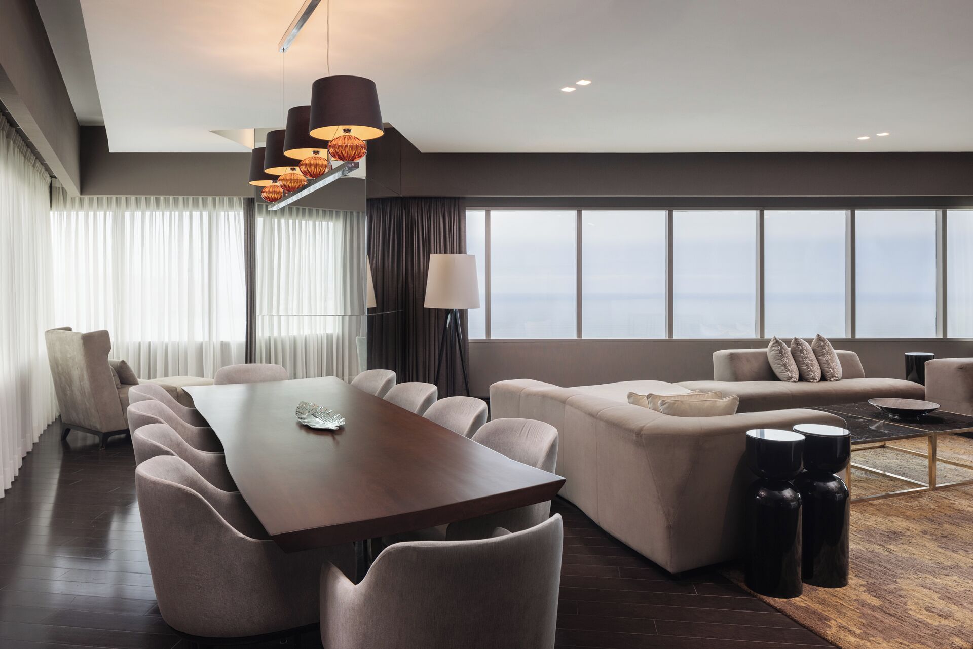 Una habitación de hotel moderna con comedor, sofá y vistas a la ciudad.