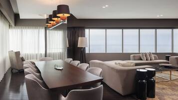 Una habitación de hotel moderna con comedor, sofá y vistas a la ciudad.