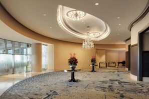 A spacious lobby with a curved ceiling, a grand chandelier, and a piano.