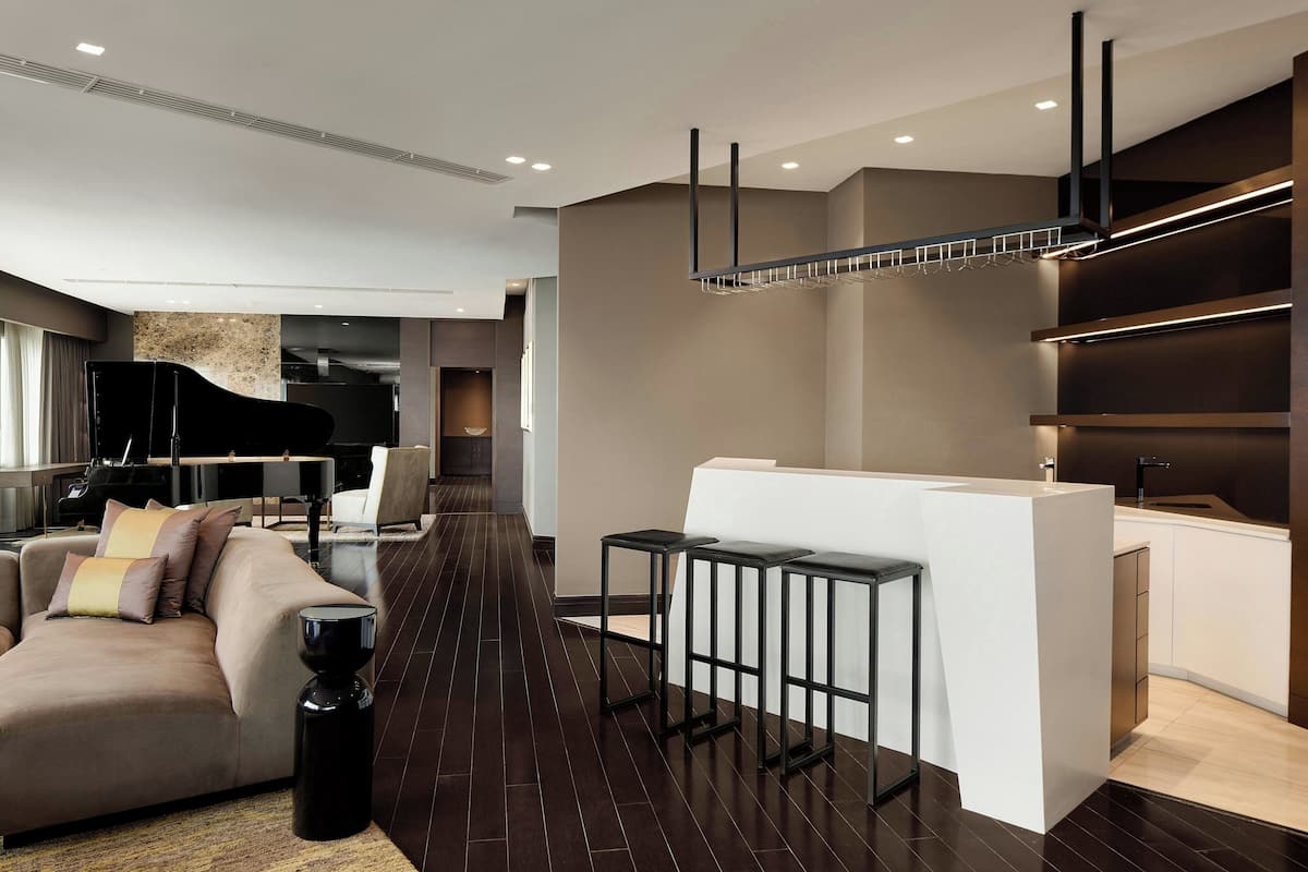A modern living room with a sofa, a coffee table, and a piano in the background.