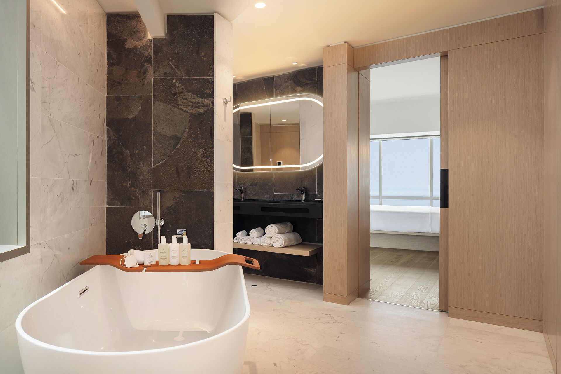 A modern bathroom with a freestanding bathtub, a vanity with a mirror, and a towel rack.