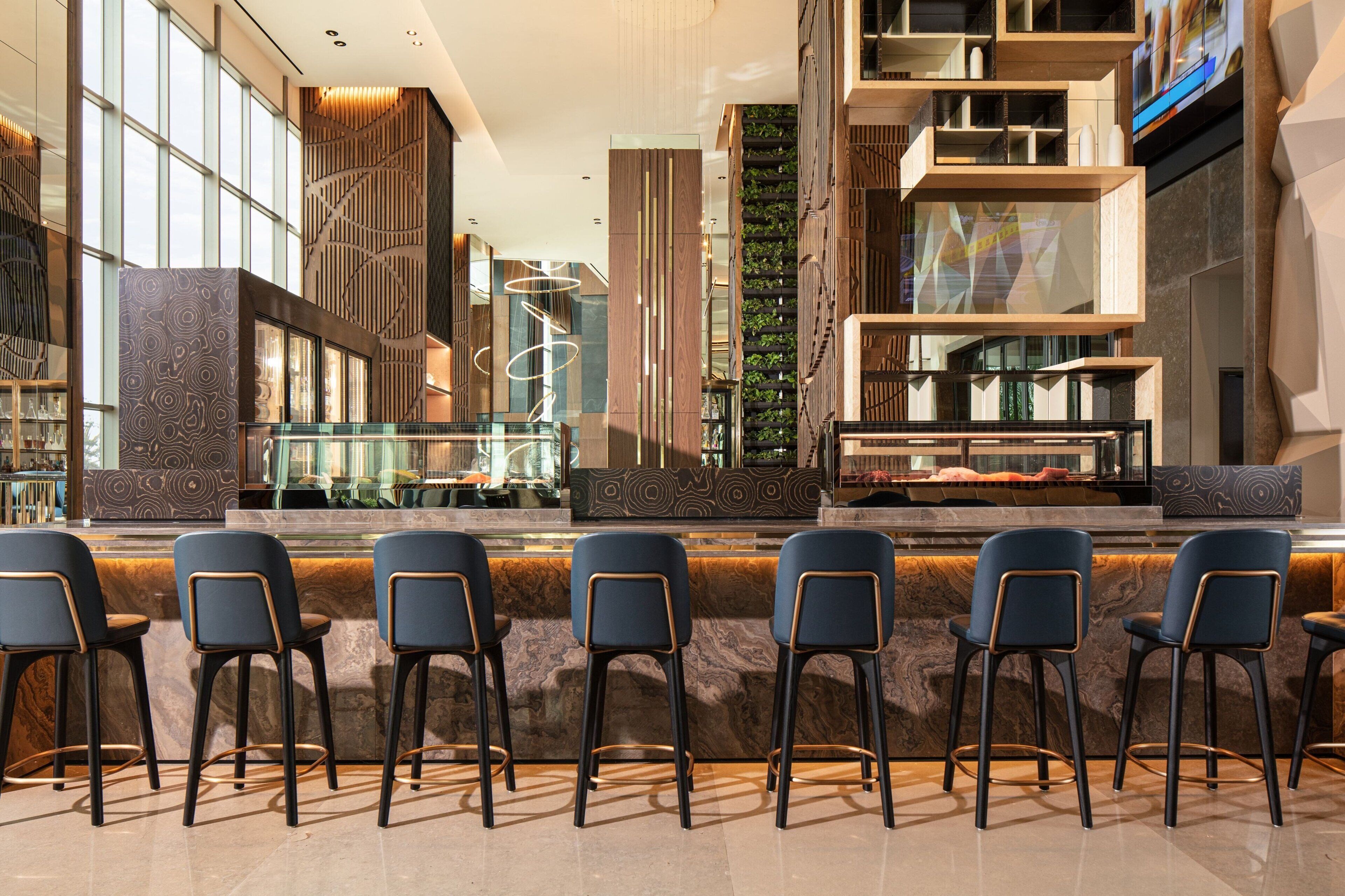 A modern bar area with a marble countertop and six bar stools.