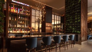 A modern bar area with a long counter, multiple shelves of bottles, and bar stools.