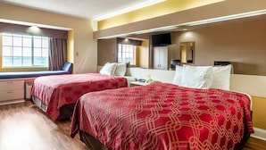 Habitación de hotel con dos camas, una ventana con cortinas, un escritorio, una silla, un televisor y un espejo.