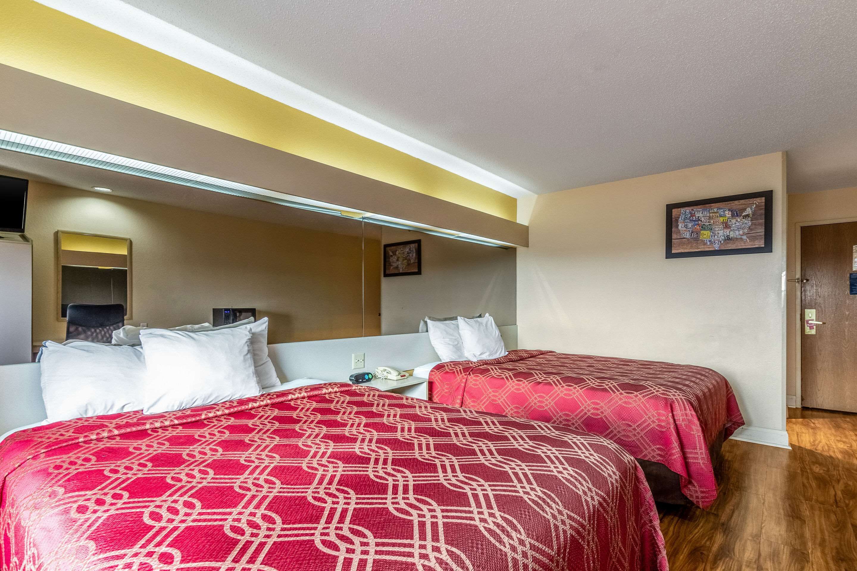 Una habitación de hotel con dos camas, una mesita y un espejo.