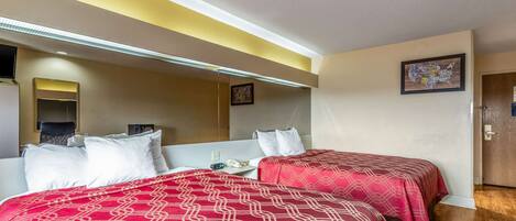 Una habitación de hotel con dos camas, una mesita y un espejo.