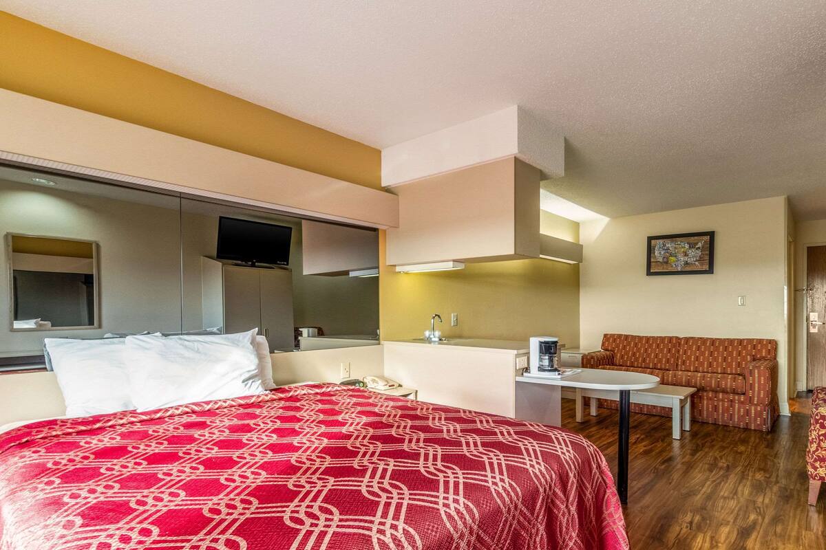 Una habitación de hotel con cama, escritorio, sofá y televisor.