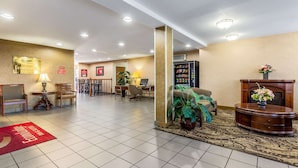 Un hall de hotel con mostrador de recepción, zona de estar y chimenea.