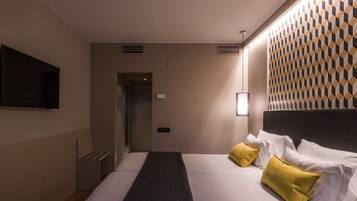 A hotel room with a bed, a TV mounted on the wall, and a patterned wall design.