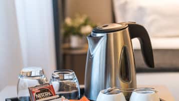 A tray with a coffee maker, two cups, a glass, and some coffee packets in a hotel room.