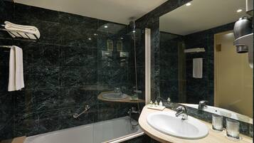 A modern bathroom with a bathtub, sink, and large mirror.