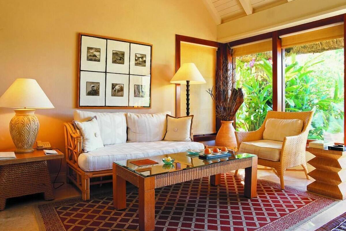 A well-lit room with a sofa, two chairs, a coffee table, and a wall-mounted picture frame.