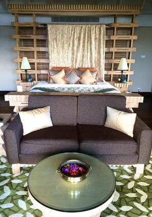 A bedroom with a bed, a sofa, a coffee table, and a wooden headboard.