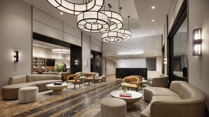Un moderno vestíbulo de hotel con un sofá modular, otomanos redondos, una mesa de centro y una chimenea.