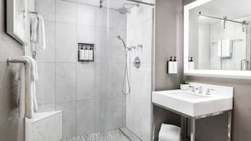 A modern bathroom with a glass-enclosed shower, a white sink, and a large mirror.