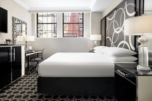 Hotelkamer met een groot bed, een bureau, een stoel, een televisie en een raam met uitzicht op de stad.