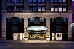 A building with a prominent 'MUSE' sign, large windows, and potted plants at the entrance. - The Muse New York (New York)