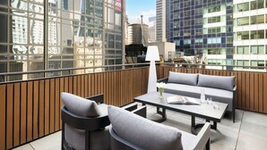 Un espacio al aire libre moderno con una zona de estar que incluye un sofá, sillas, una mesa y una lámpara.