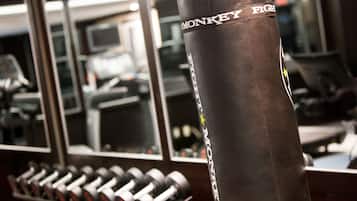 Un gimnasio con un saco de boxeo que dice 'MONKEY FIGHT' y un estante con mancuernas.