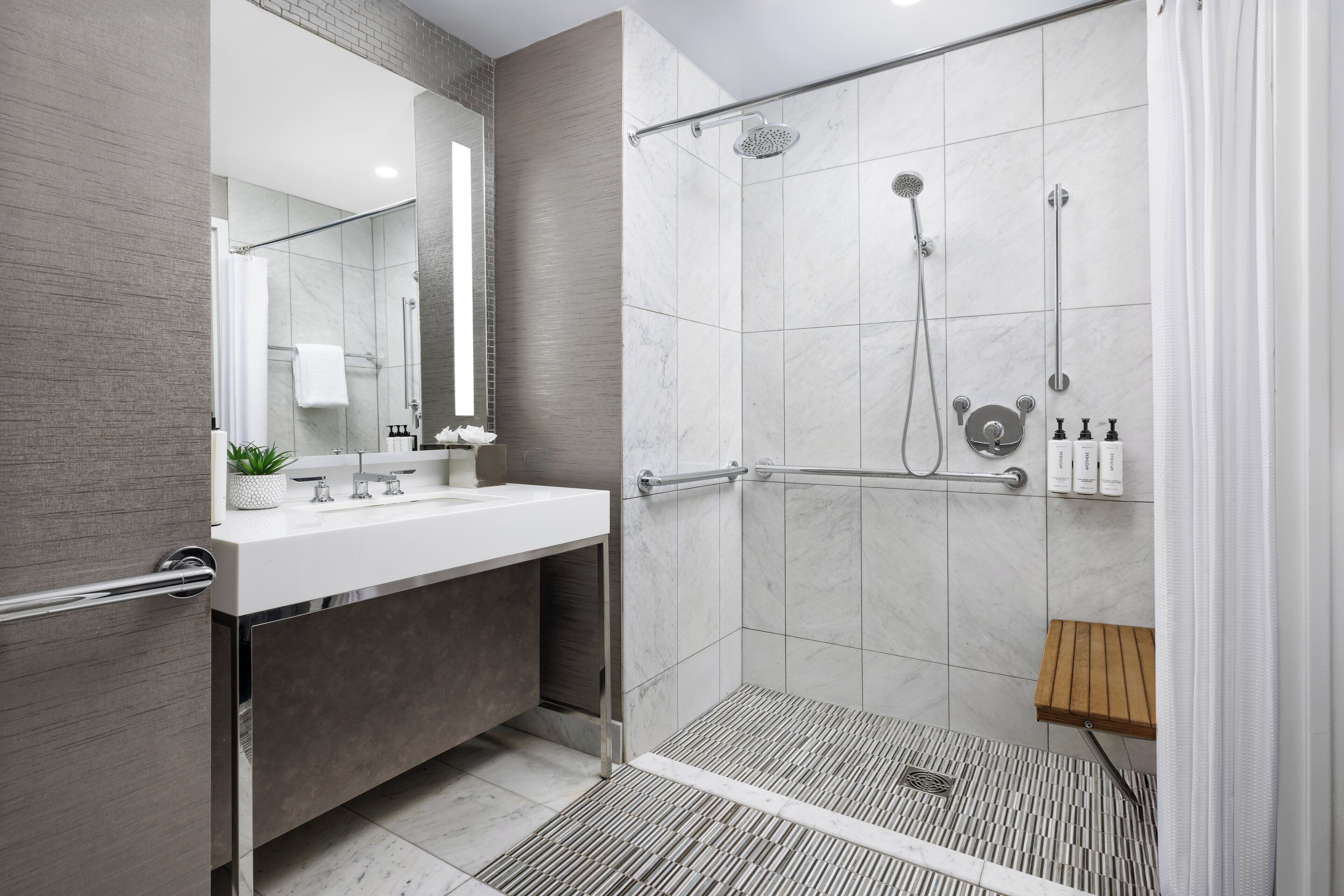 A modern bathroom with a shower, a sink, and a mirror.