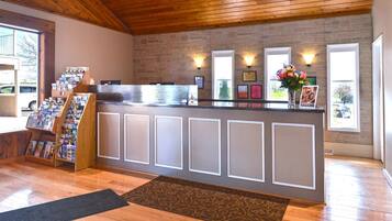 A reception area with a wooden ceiling, a reception desk, a bulletin board, and a window with a view of the outside.