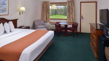 A hotel room with a large bed, a desk, a chair, a television, and a window with curtains.