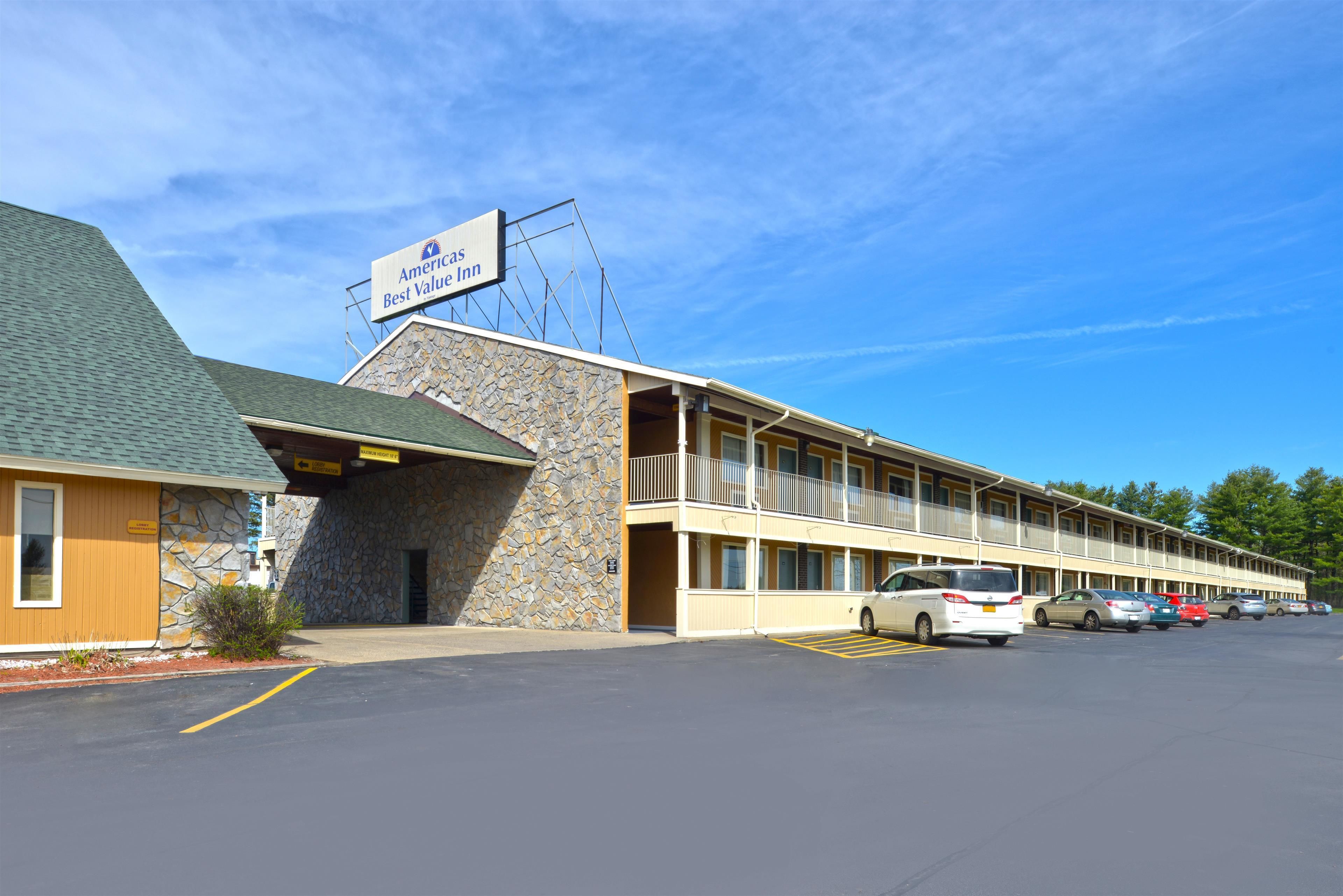 A motel with a stone facade, a sign reading "American Inn Best Value Inn," and a parking lot with several cars.