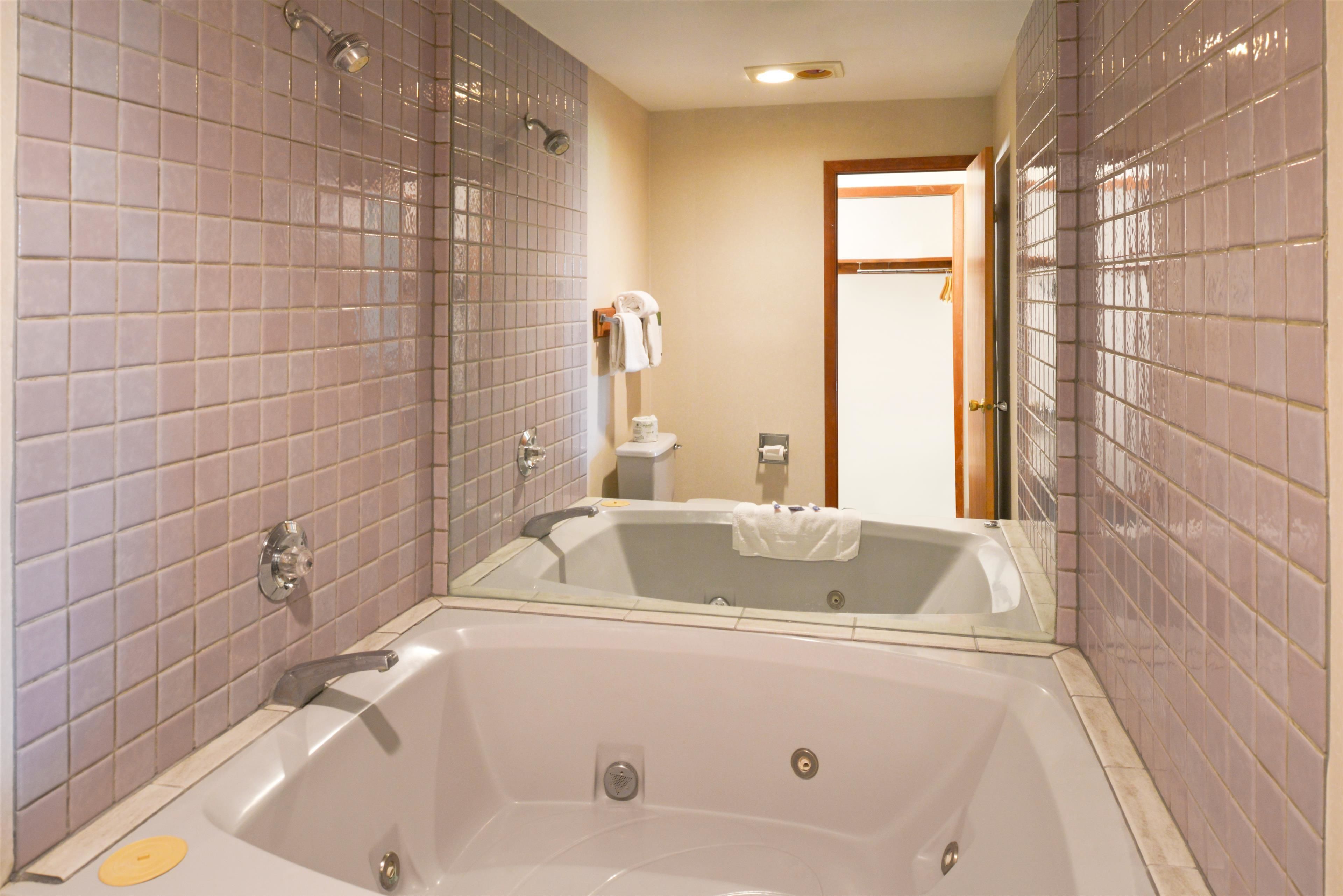 A bathroom with a large bathtub, tiled walls, and a visible toilet and towel rack.