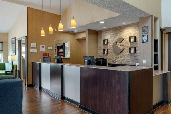 A reception area with a wooden reception desk, pendant lighting, and a stone wall with a large 'C' logo.