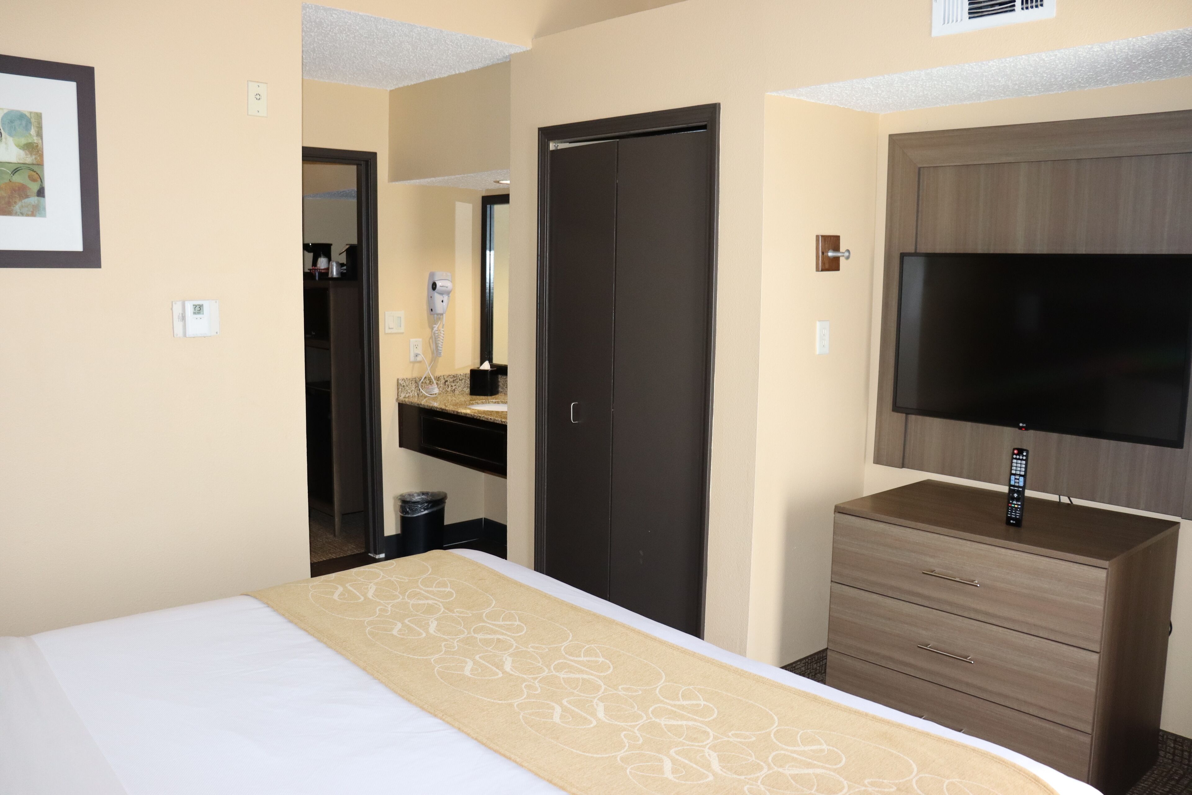 Una habitación de hotel con cama, cómoda, televisión y puerta.