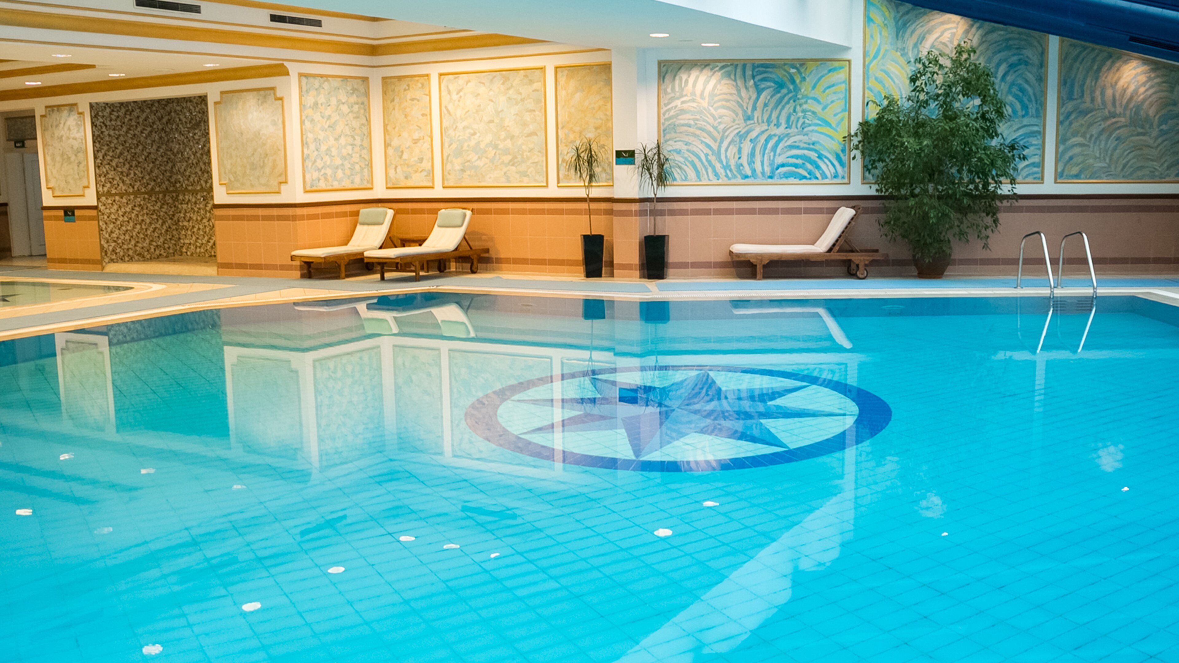 A swimming pool with lounge chairs and a decorative wall.