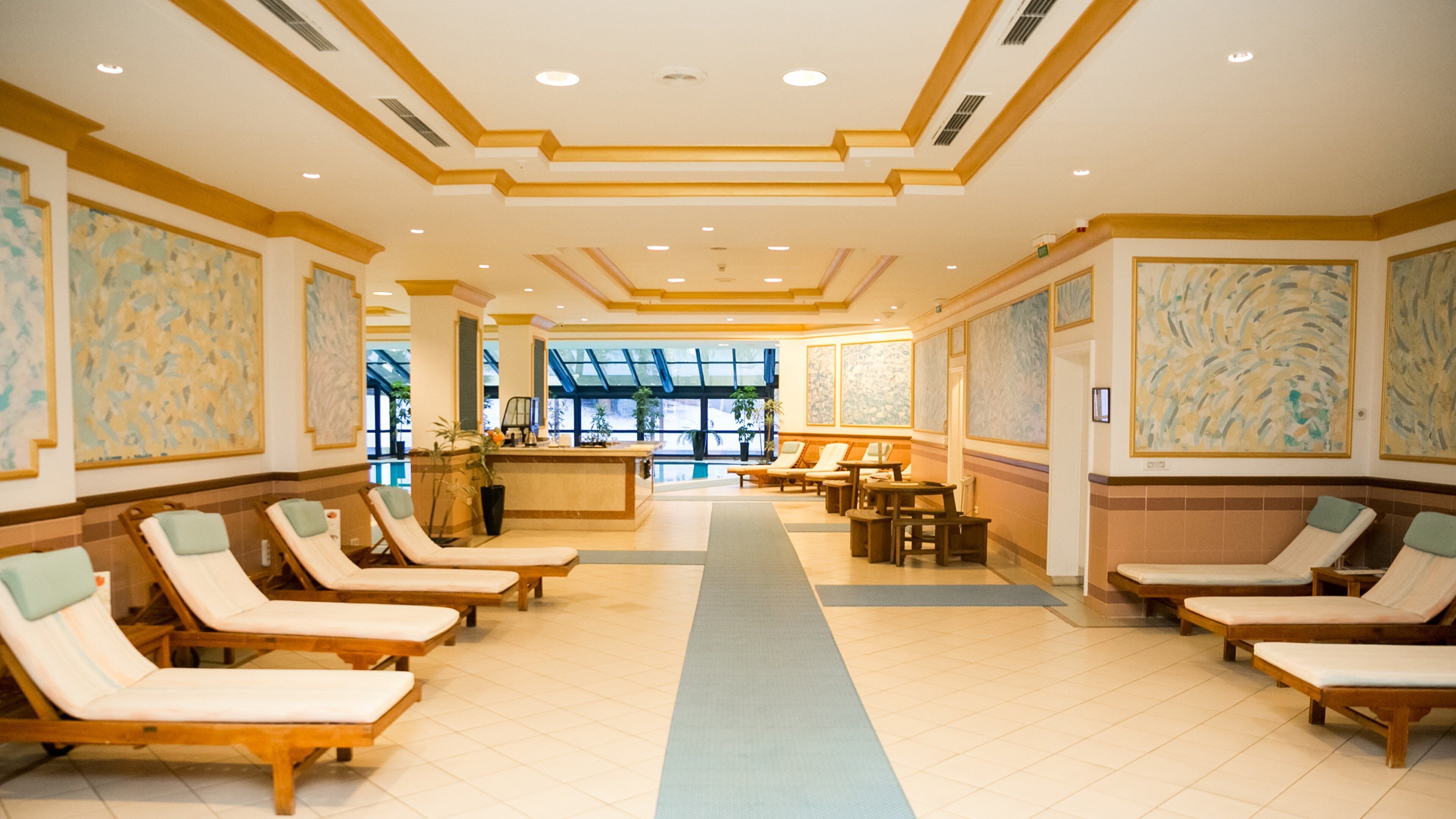 Eine Hotelhalle mit Liegestühlen, einer Rezeption und großen Fenstern.